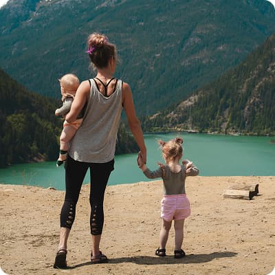 Woman holding two babies (one on ground, one carried) – family security via future planning in Bonsai AI financial planning